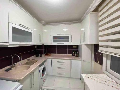 a white kitchen with a sink and a dishwasher at Ferah ve şık cosy daire in Konak