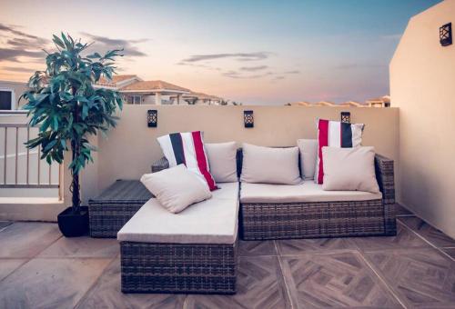 a patio with wicker furniture and a potted plant at Paradise Coast PR Rooftop Suite in Isabela