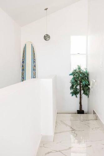 a surfboard in a white room with a potted plant at Paradise Coast PR - Vista Mar in Isabela