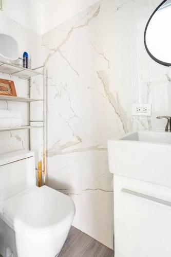 a white bathroom with a toilet and a sink at Paradise Coast PR - Vista Mar in Isabela