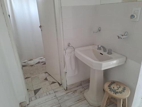 Baño blanco con lavabo y taburete en 155 Apartamento en Alta Gracia