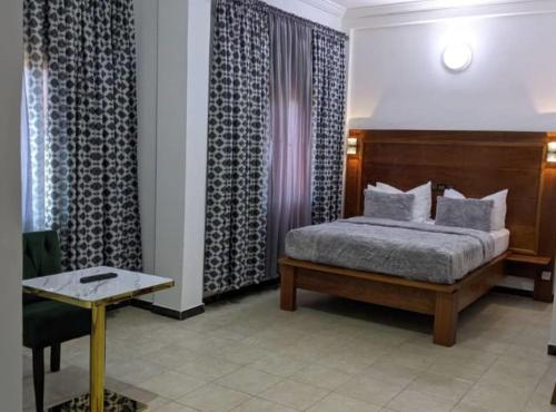 1 dormitorio con cama, mesa y cortinas en JAD HOTEL Dschang, en Dschang