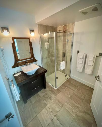 a bathroom with a sink and a shower with a mirror at Auberge Spa & Beaux Reves in Sainte-Adèle