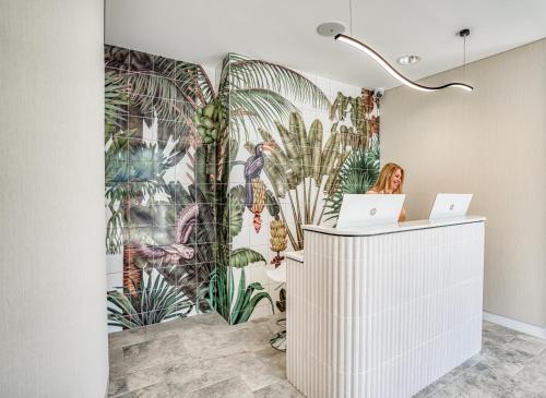 a woman is sitting at a desk in front of a mural of plants at Essence Peregian Beach Resort - Lily 4 Bedroom Luxury Home with Private Pool in Peregian Beach