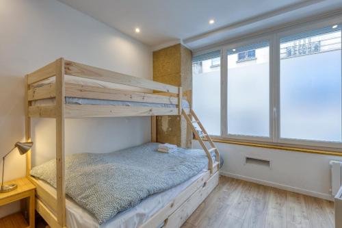 Les Vignes de Montmartre - Studio في باريس: سرير بطابقين في غرفة بها نافذتين