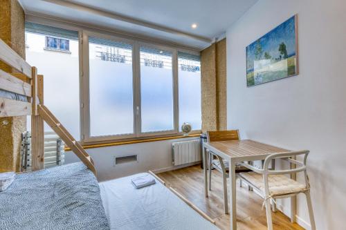 Habitación con escritorio, cama y ventanas. en Les Vignes de Montmartre - Studio, en París