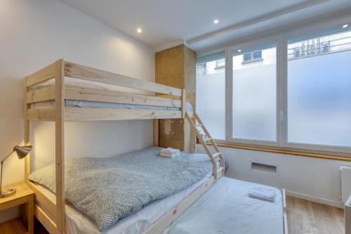Les Vignes de Montmartre - Studio في باريس: سرير بطابقين في غرفة بها نافذتين