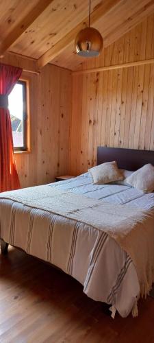 Un dormitorio con una cama en una habitación de madera. en Acun Lihuen, en Cobquecura