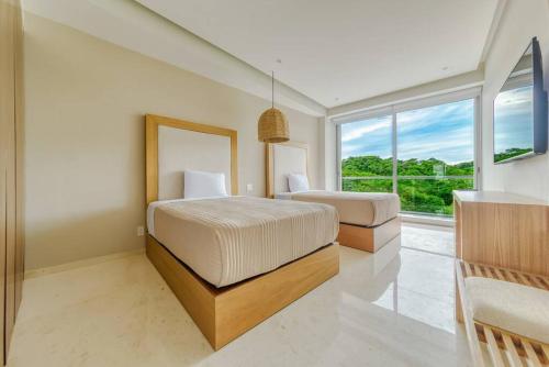 ein Schlafzimmer mit zwei Betten und einem großen Fenster in der Unterkunft New 3BR Condo - Oceanview Terrace - Private Beach in Higuera Blanca