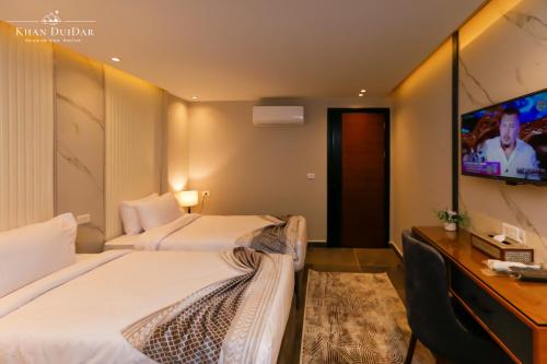 a hotel room with two beds and a television at Khan Duidar Inn - Pyramids View Rooftop in Cairo