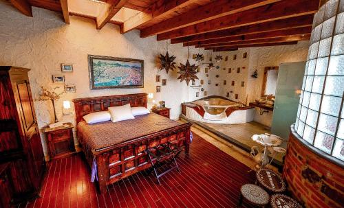 a bedroom with a bed and a tub in a room at Hacienda Tepetlcalli 1870 Hotel Museo & Spa in Tepeyahualco