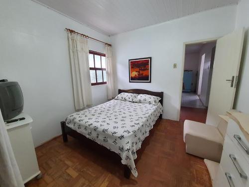a bedroom with a bed and a tv in it at Casa no Centro - Perto do mar e do rio in Tramandaí