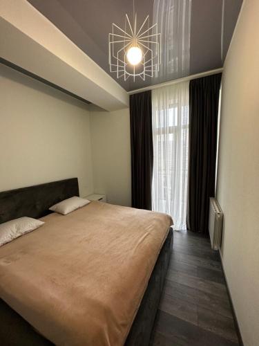a bedroom with a large bed and a chandelier at Jikia Residence in Tbilisi City