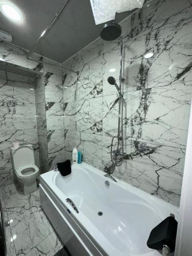 a bathroom with a white tub and a toilet at Jikia Residence in Tbilisi City