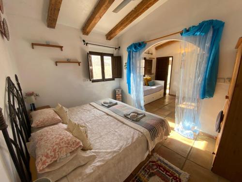 1 dormitorio con 1 cama con cortinas azules en Casita El Aljibe en Gebas