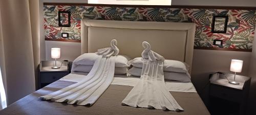 Welcome to I Colori di Napoli في نابولي: غرفة نوم فيها بجعتين بيضاء على سرير