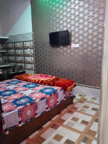 a bedroom with a bed with a tv on the wall at Balaji homestay Mathura in Vrindavan in Mathura