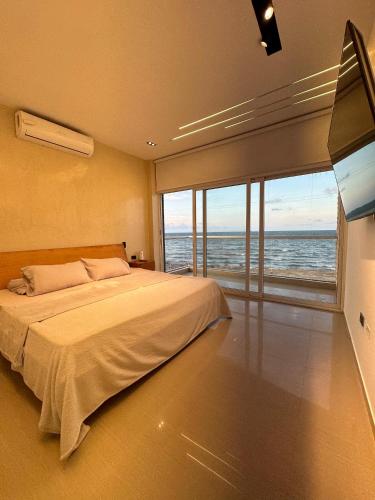 a bedroom with a large bed and a large window at Cabaña la arenosa in Barranquilla