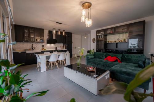 a living room with a green couch and a kitchen at Spacious apartment near the beach in Bordeaux