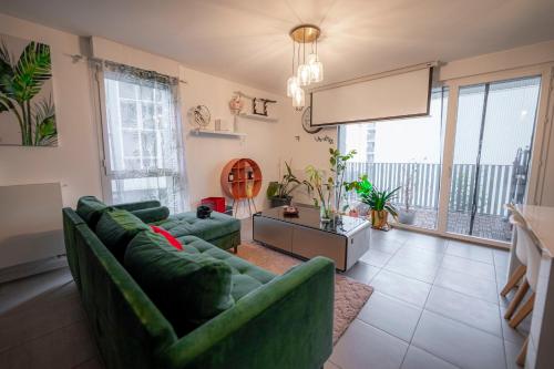 una sala de estar con sofás verdes y una ventana grande en Spacious apartment near the beach en Burdeos