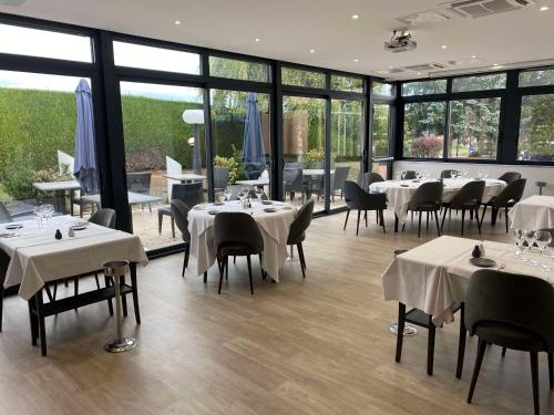 un restaurante con mesas y sillas blancas y ventanas en Best Western Plus La Fayette Hotel et SPA, en Épinal