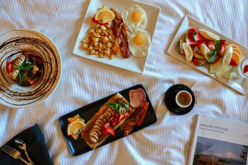 a table with three plates of food and a magazine at Hôtel Québec Best Western PLUS Centre-Ville - City Center in Quebec City