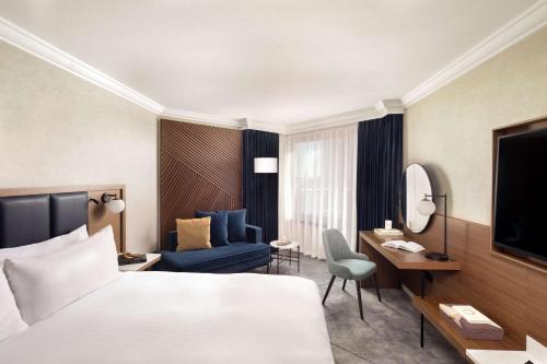 Cette chambre comprend un grand lit et un canapé. dans l'établissement Hilton London Metropole, à Londres