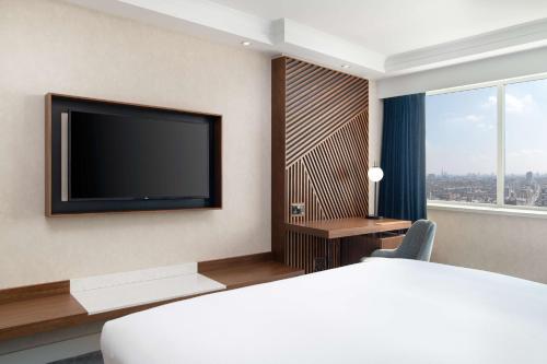 a hotel room with a bed and a flat screen tv at Hilton London Metropole in London