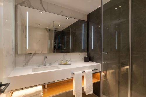 a bathroom with a sink and a glass shower at Hilton London Metropole in London