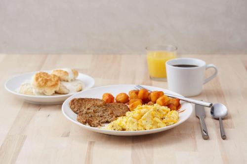 two plates of breakfast food on a wooden table at Pear Tree Inn St Louis Convention Center in Saint Louis