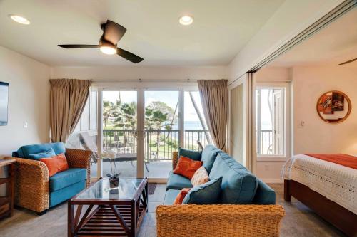 a living room with a blue couch and a bed at Waipouli Beachfront Condo with Balcony and Ocean Views in Kapaa