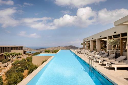 a pool at the resort with lounge chairs at Domes Aulus Elounda, All Inclusive, Adults Only, Curio Collection by Hilton in Elounda