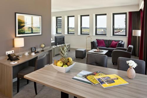 a living room with a table and a living room with a couch at Fletcher Hotel-Restaurant Wings-Rotterdam in Rotterdam
