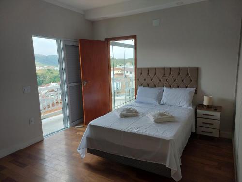 a bedroom with a bed and a large window at Alto Padrão! Vista linda! Churrasqueira! Hidro! in Poços de Caldas