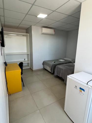 a room with a bed and a white refrigerator at Hotel Brasília - centro in Brasilia