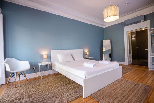 a bedroom with a white bed and a blue wall at VAGO Alcântara Suites in Lisbon