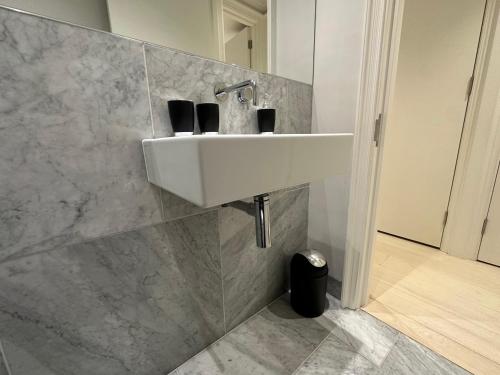 een badkamer met een witte wastafel aan de muur bij Chic Covent Garden Apartment By Sloanes Group in Londen