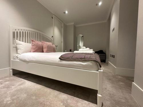 een slaapkamer met een groot wit bed met roze kussens bij Chic Covent Garden Apartment By Sloanes Group in Londen