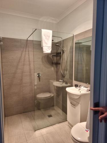 a bathroom with a shower and a toilet and a sink at Myrtleford Hotel in Myrtleford