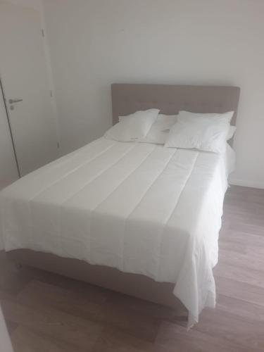 a white bed with white sheets and pillows at Villa93 in Villepinte