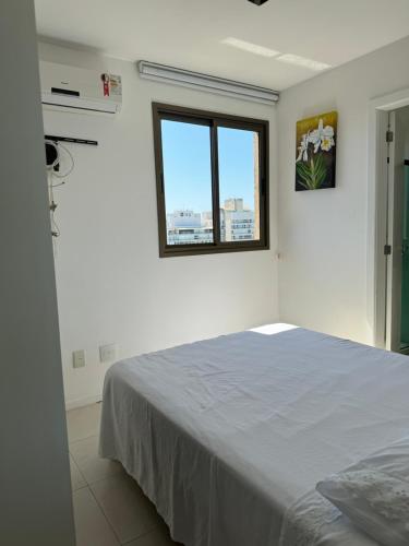 ein weißes Zimmer mit einem Bett und einem Fenster in der Unterkunft Apartamento perto da praia em Itapoã in Vila Velha
