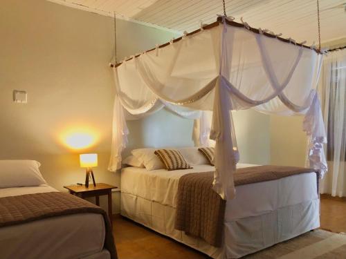 a bedroom with two beds and a canopy bed at Pousada Jardins in Santarém