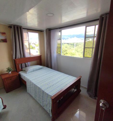 a small bedroom with a bed and two windows at Apartamento con vista a la ciudad en barrio campo hermoso 301 in Bucaramanga