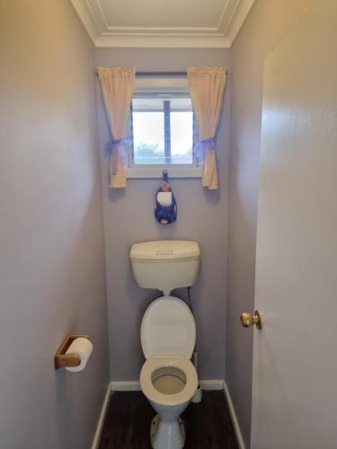 a small bathroom with a toilet and a window at Two Pines, whole home in Tullamarine near airport! in Melbourne