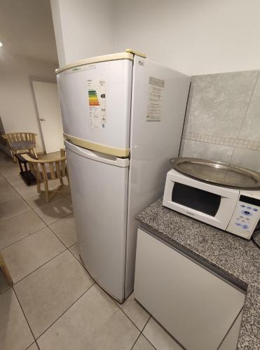 La cocina está equipada con nevera blanca y microondas. en Bauhaus departamento centro en Córdoba