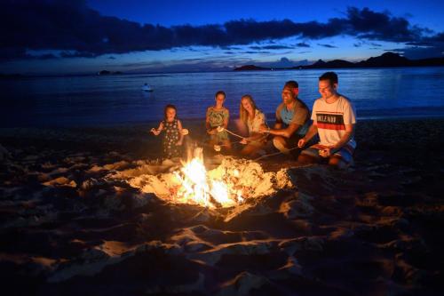 a group of people sitting around a fire on the beach at Sheraton Resort & Spa, Tokoriki Island, Fiji in Tokoriki