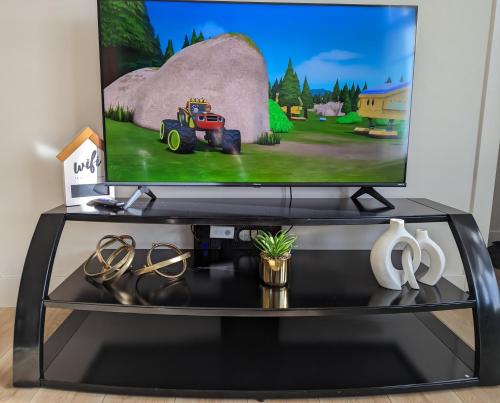 a tv screen on a black entertainment center at Comfy 2BR condo in Seton, Southeast Calgary in Calgary