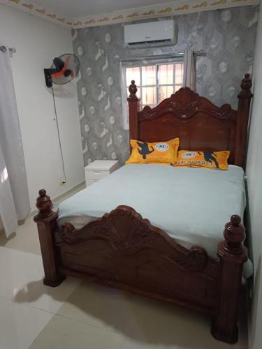 Un dormitorio con una gran cama de madera con almohadas amarillas. en Apartamento Vista Sur, en Baní
