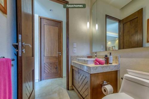 a bathroom with a sink and a toilet and a mirror at Chic Studio w/Rooftop Pool - Ocean View - King Bed in Puerto Vallarta