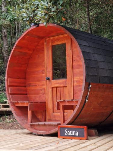 a wooden hobbit house with a door and a sign at Ecos del Manantial in Villarrica